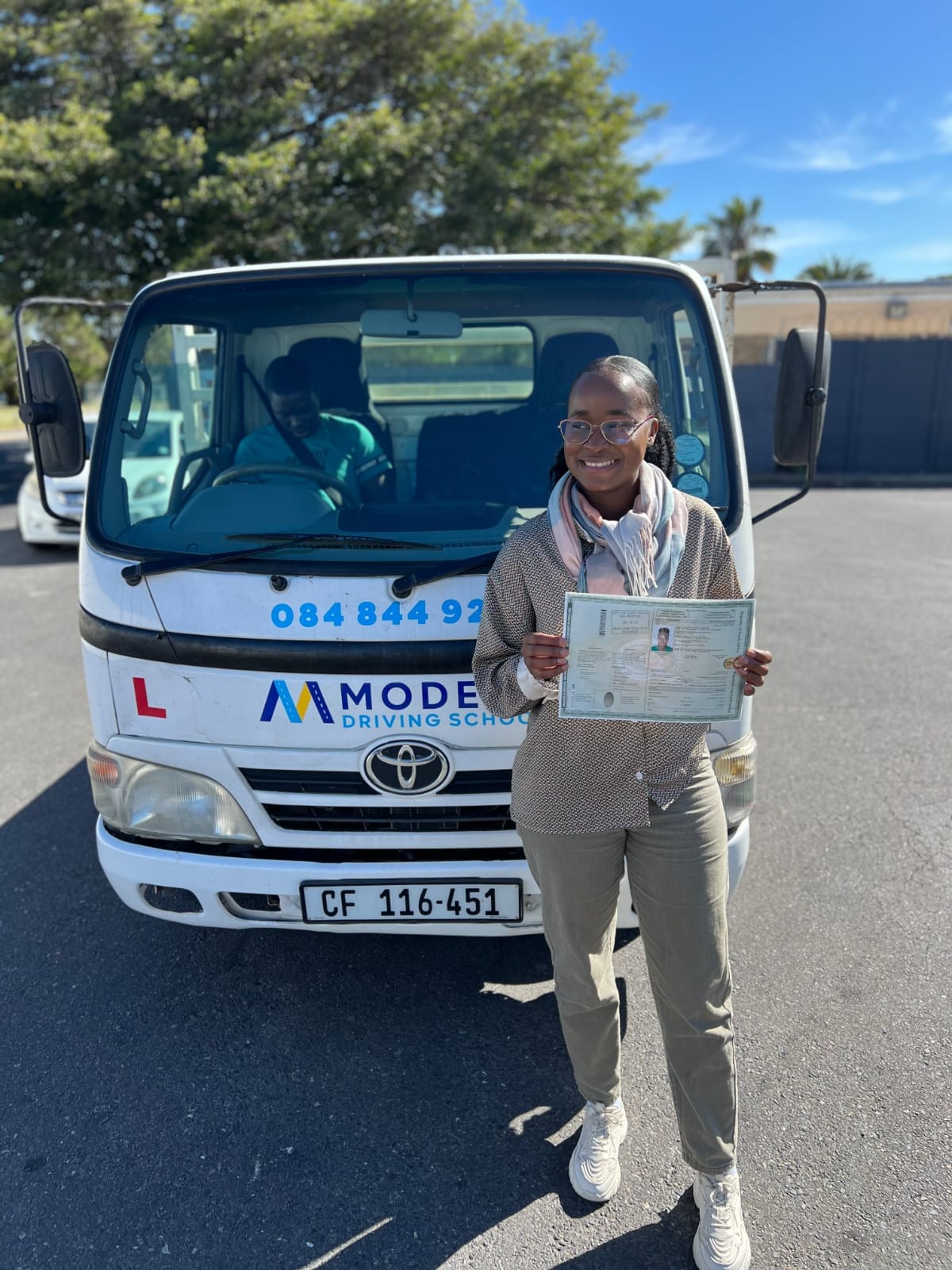 Student with her new licence in front of a Modern Driving School Code 10 truck