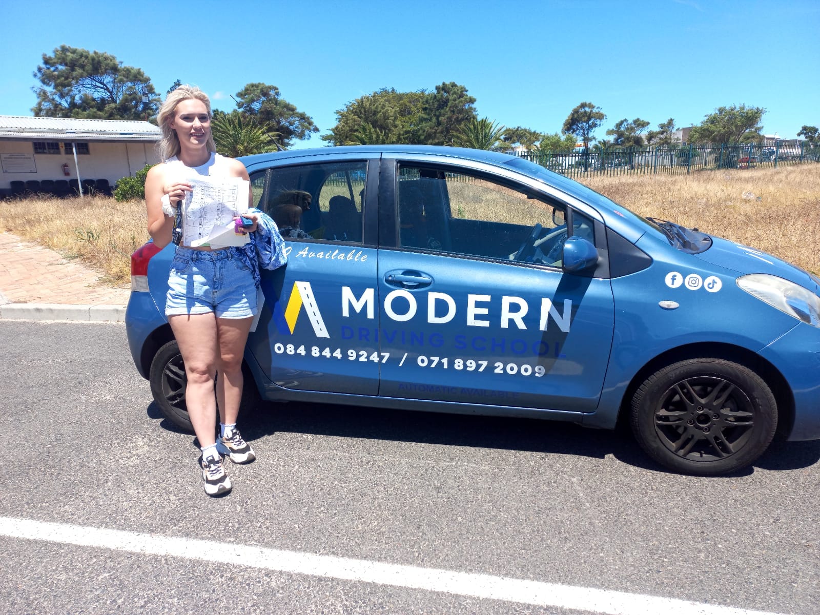Learner celebrating pass beside a Modern Driving School car