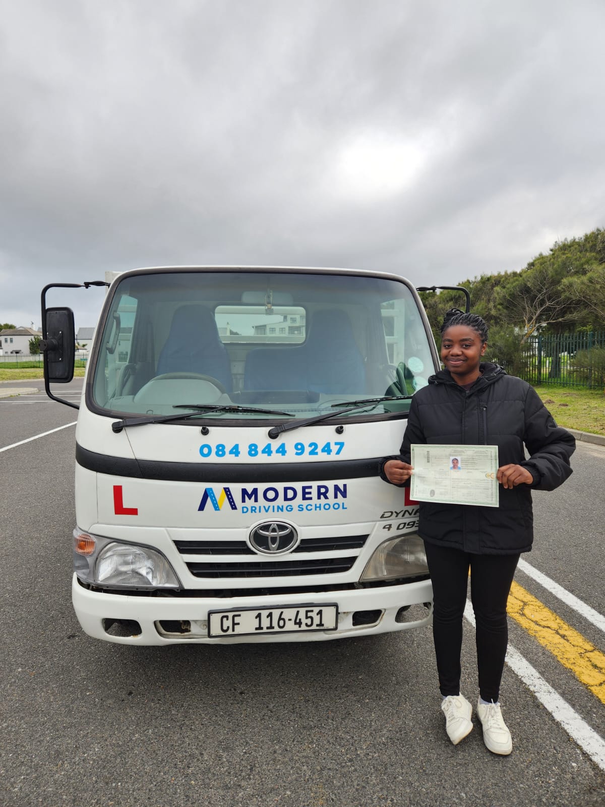 Newly licensed driver in front of a Modern Driving School truck